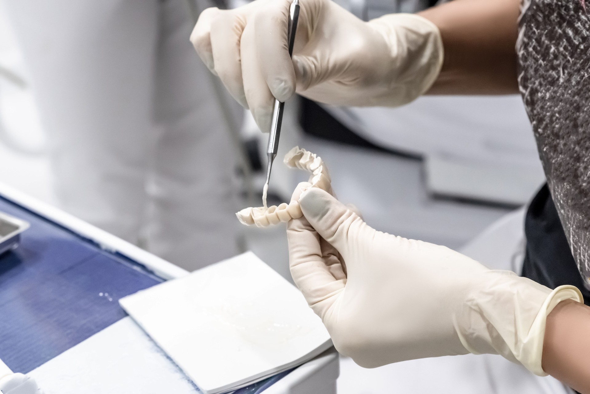 the dentist applies the solution to an artificial temporary prosthesis in the dentist office, a close-up of the hands with the prosthesis