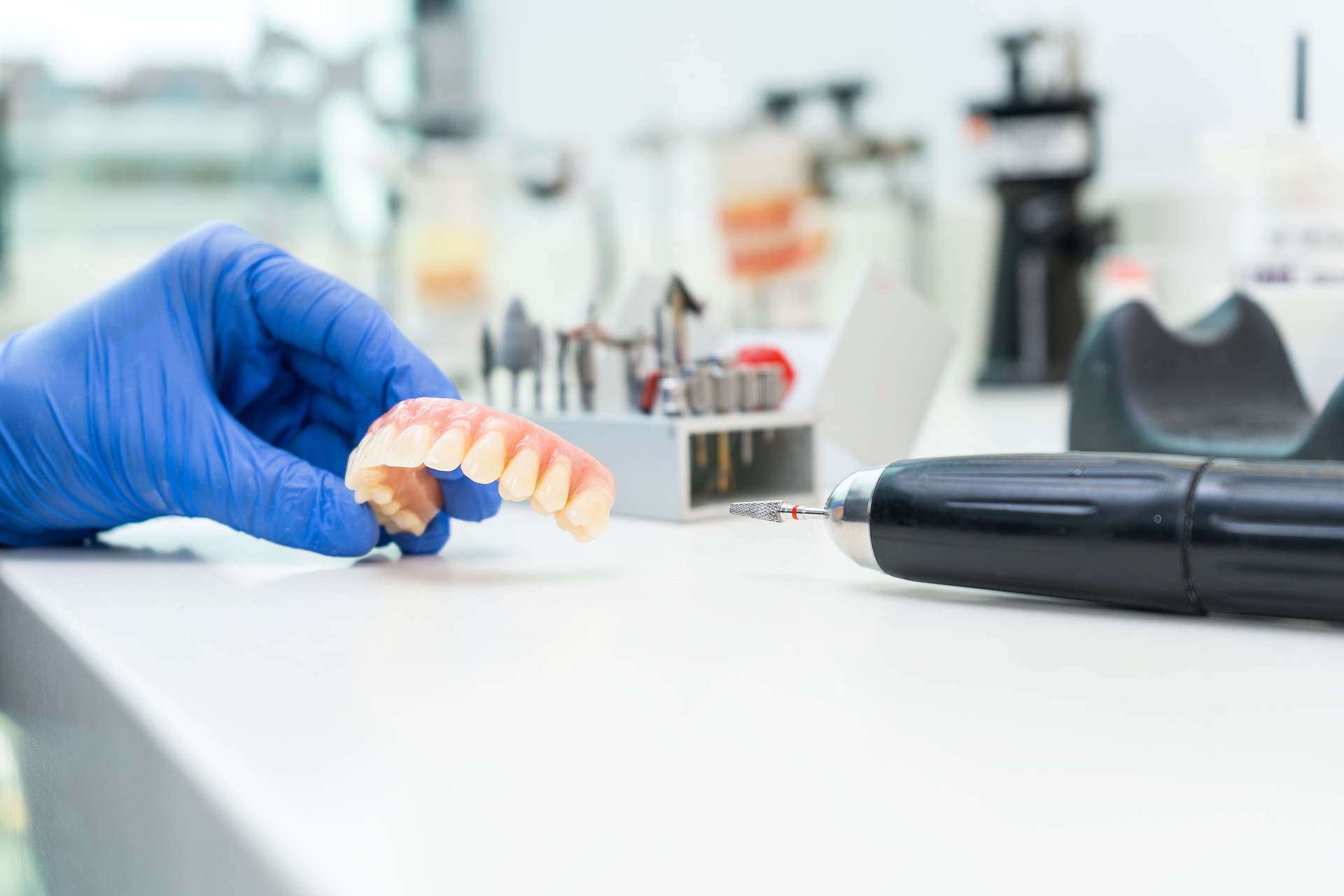 Hand holds dental prosthesis in laboratory